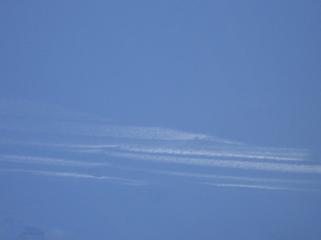 A blue sky with some white clouds and some planes