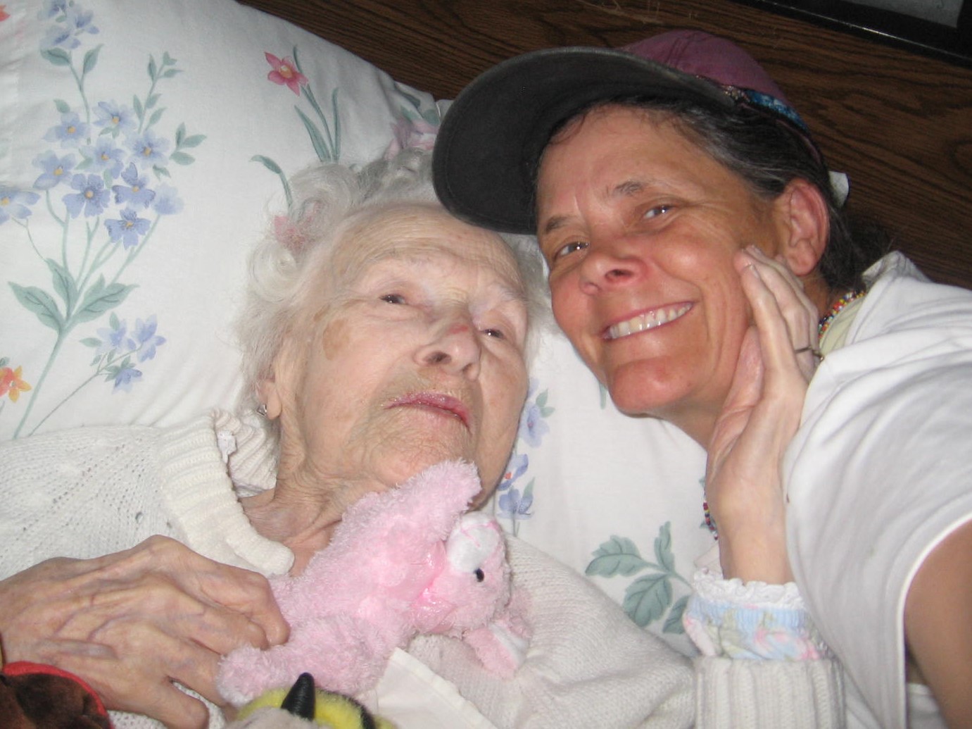 A woman and an old lady in bed smiling.