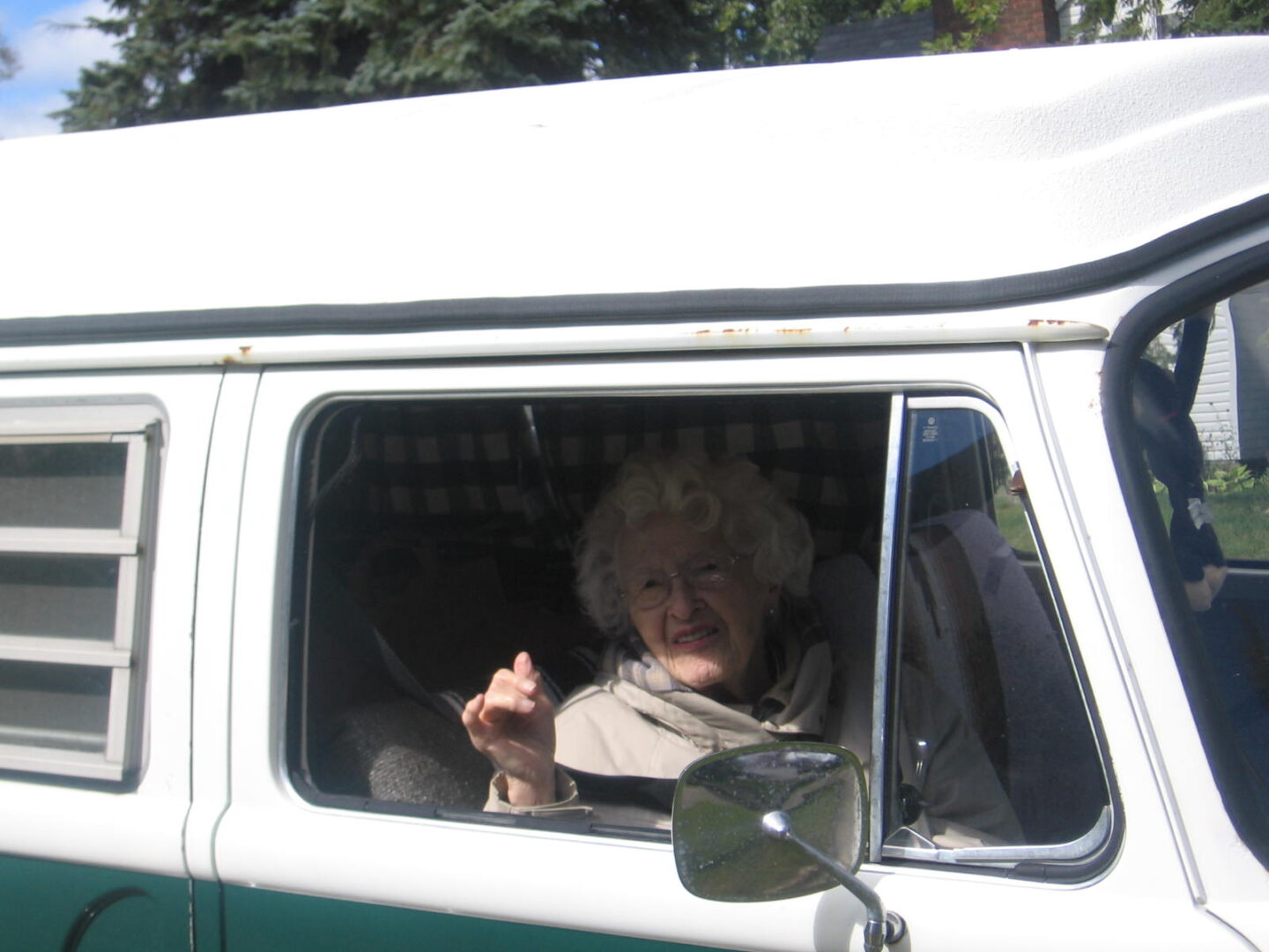 A woman sitting in the driver 's seat of an old van.