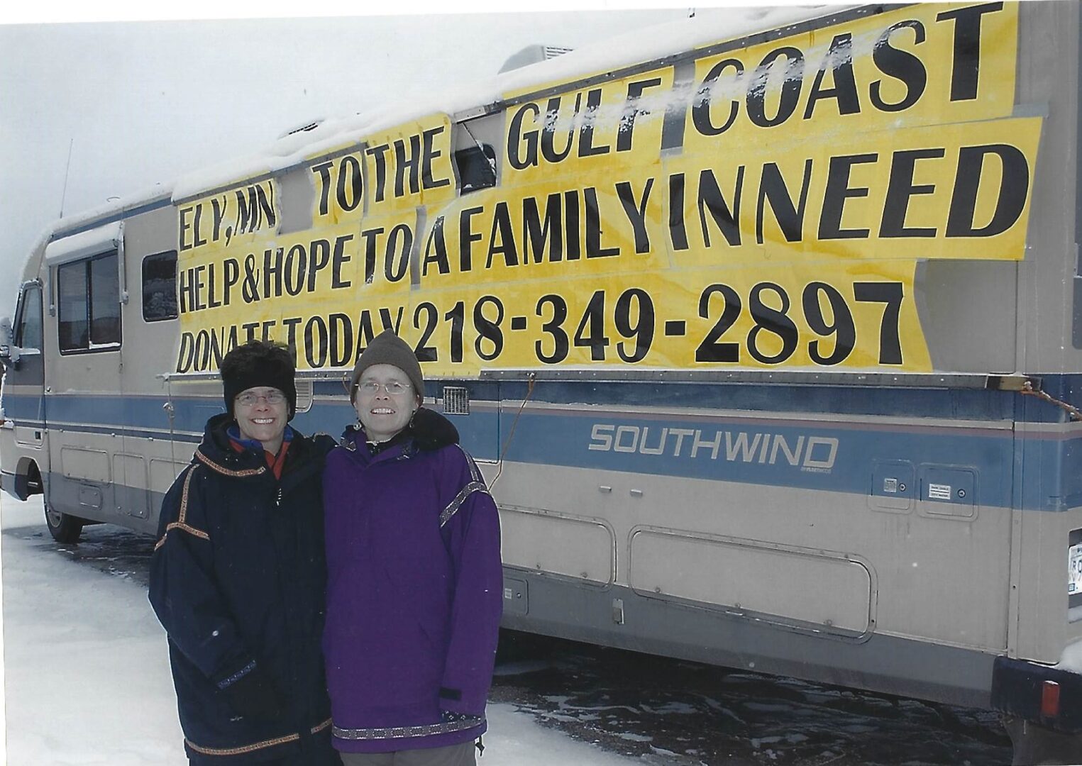 Two people standing in front of a yellow boat.