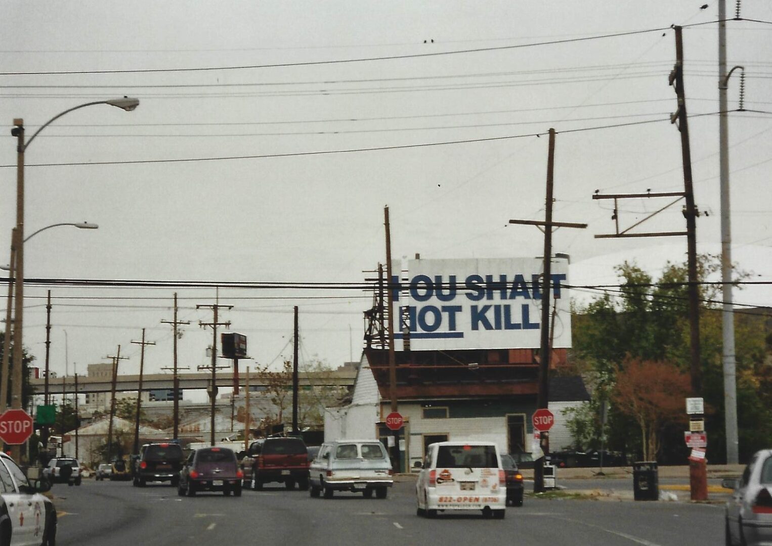 A billboard on the side of a road with cars driving down it.