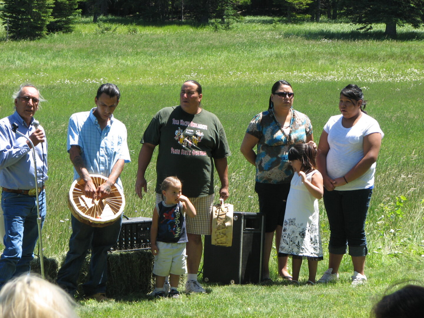 A group of people standing in the grass with some instruments.