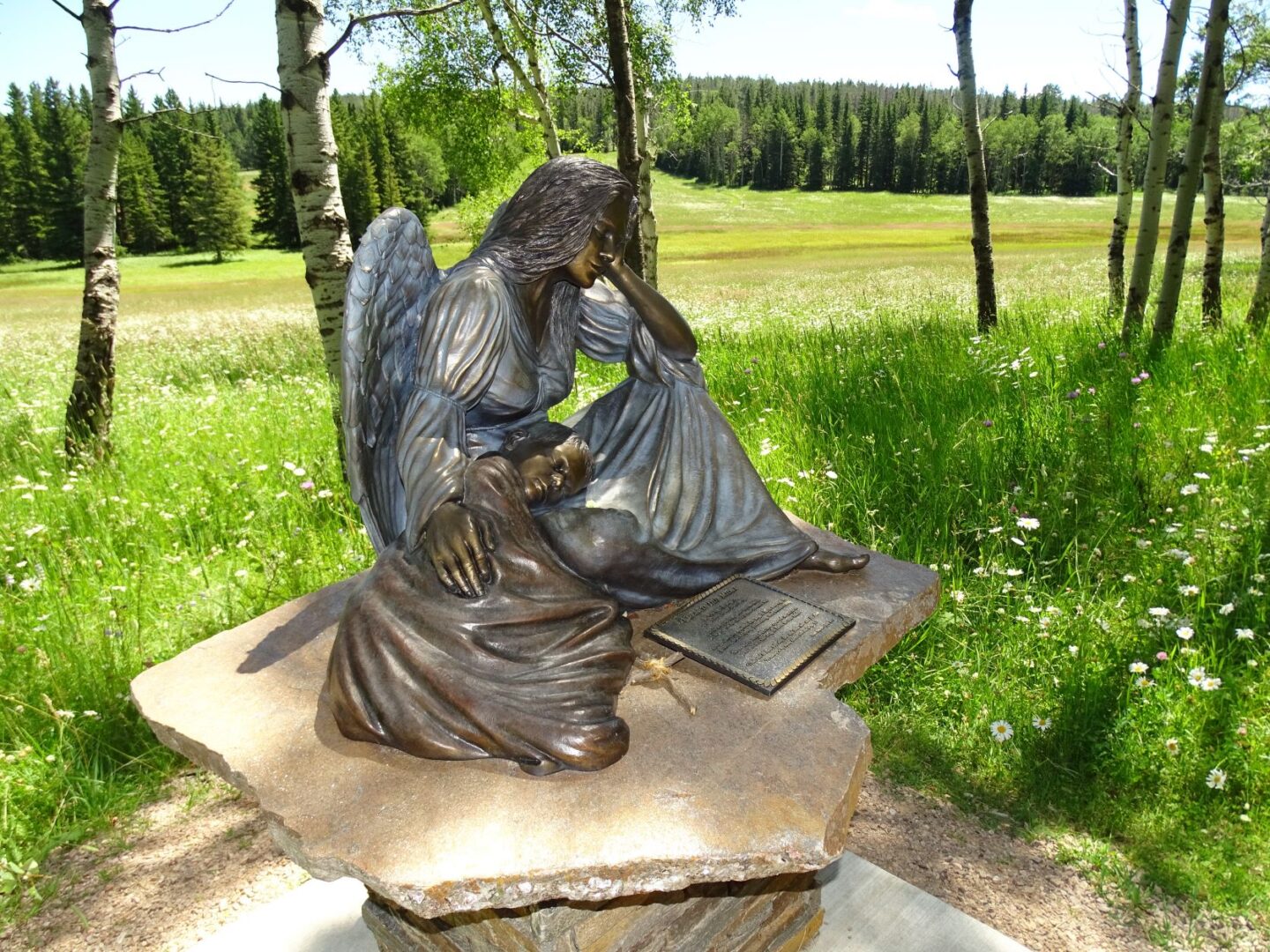 A statue of an angel sitting on top of a rock.