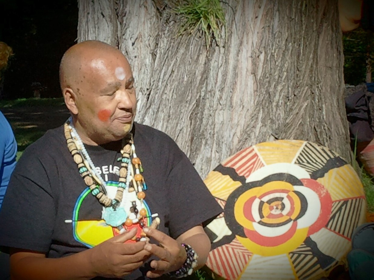 A man with an african mask on his face.