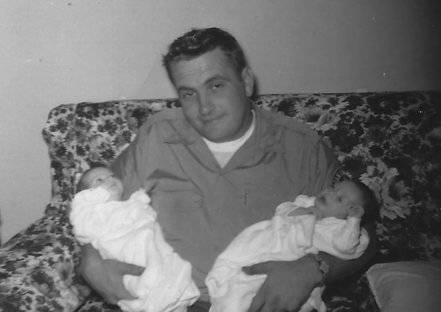 A man holding two babies on his lap.