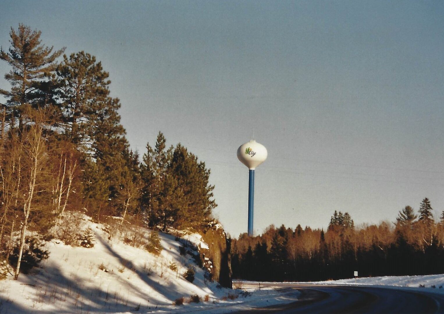 A water tower in the middle of a snowy field.