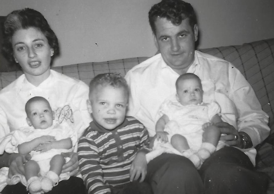 A man and woman holding two babies while sitting on the couch.