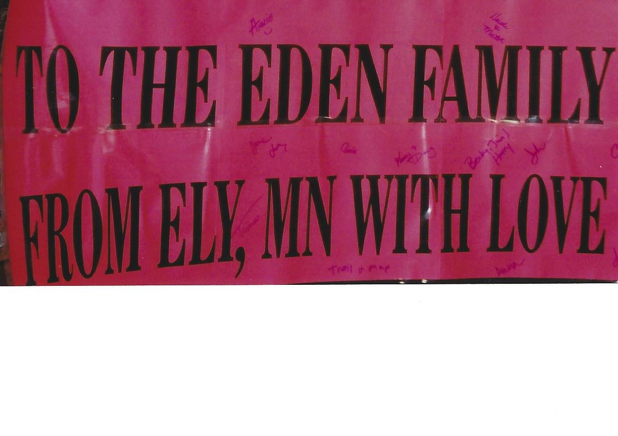 A pink banner with the words " the eden family from ely, mn with love ".