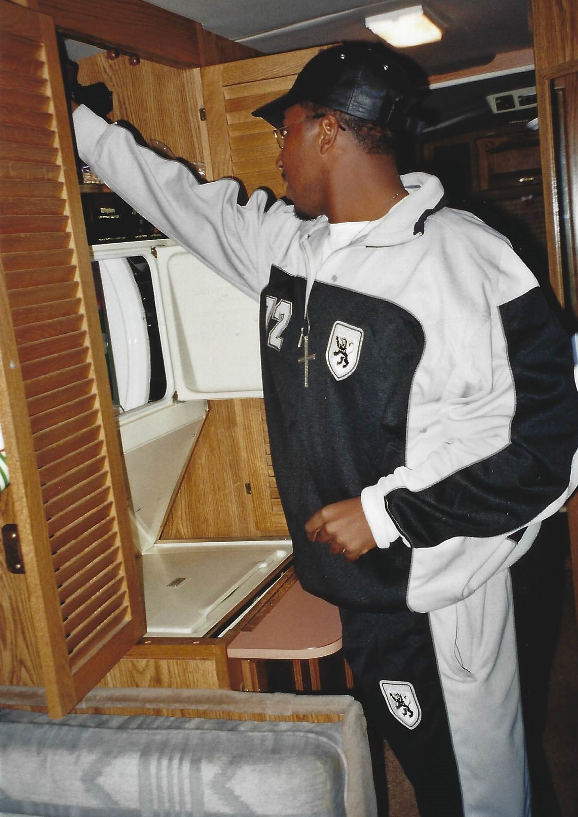 A man in black and white jacket opening the door of a kitchen.