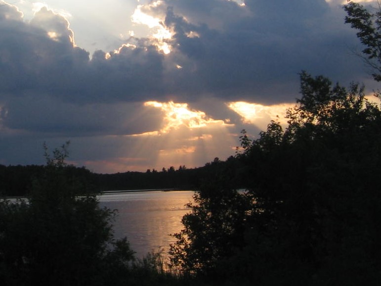 A lake with trees and clouds in the sky.