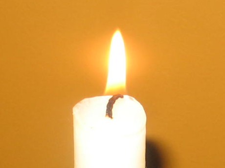 A candle is lit on the wall of a room.