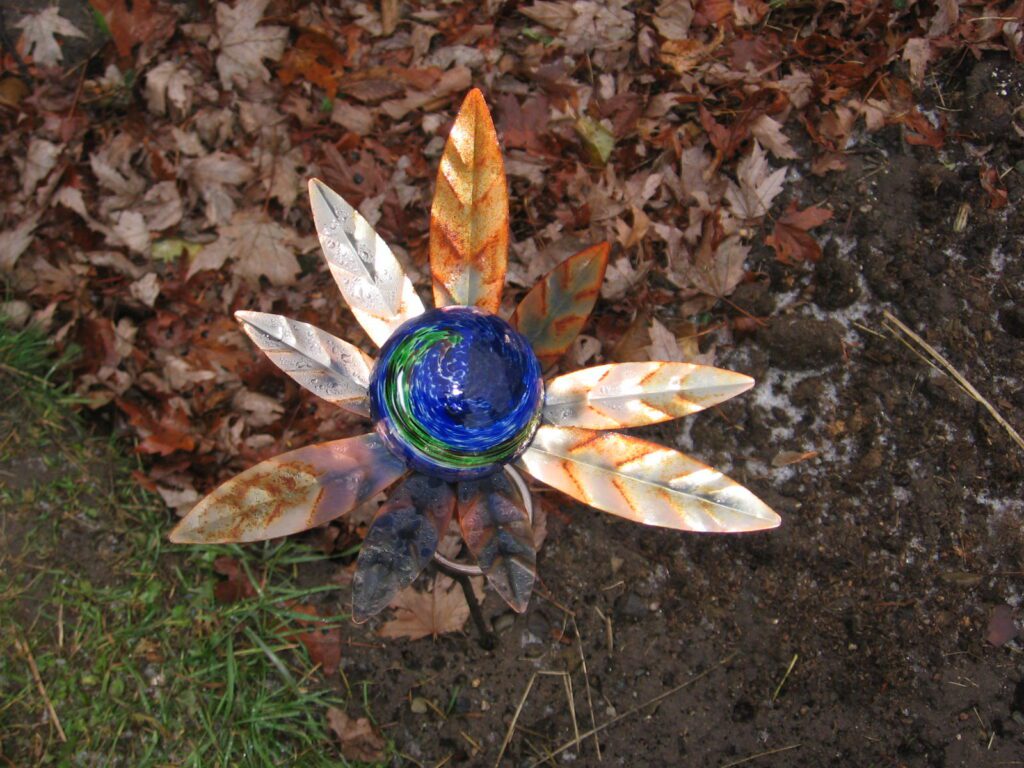 A metal flower with leaves and blue glass.