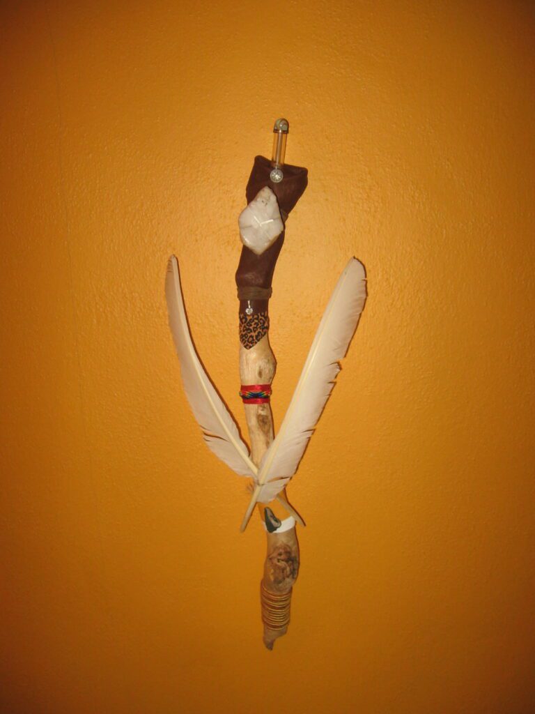 A feather and stick are hanging on the wall.