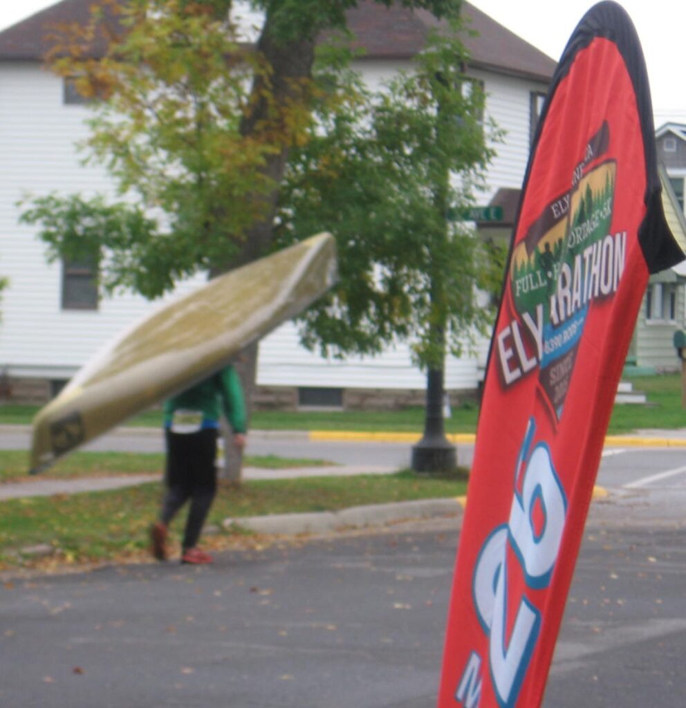 A person carrying a surfboard in the street.