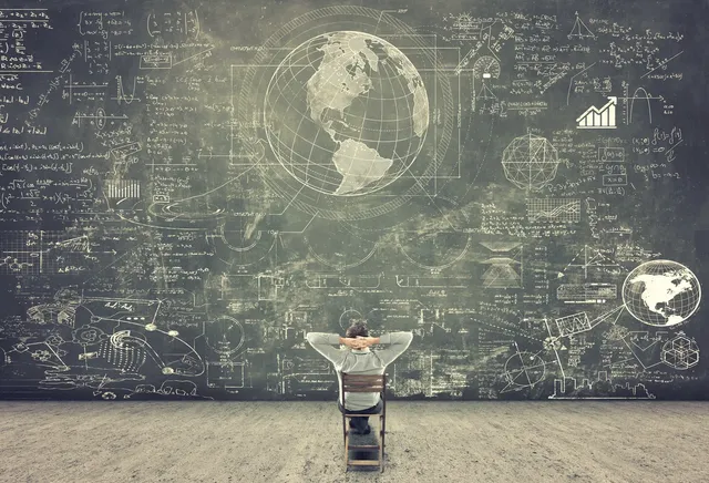 A man sitting in front of a chalkboard with a globe on it.