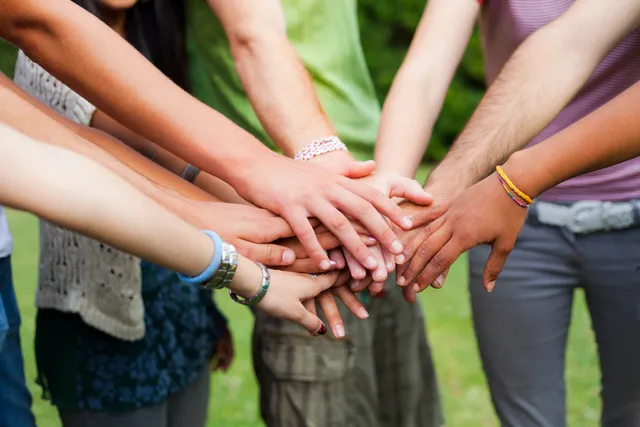 A group of people holding hands in the middle of a circle.