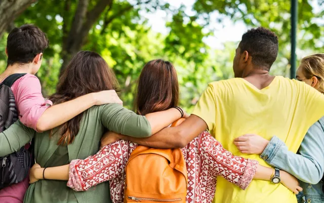 A group of people hugging each other in the park.