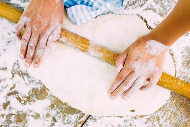 A person is making dough on the floor