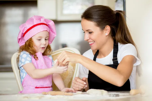 A woman and child in the kitchen making dough.