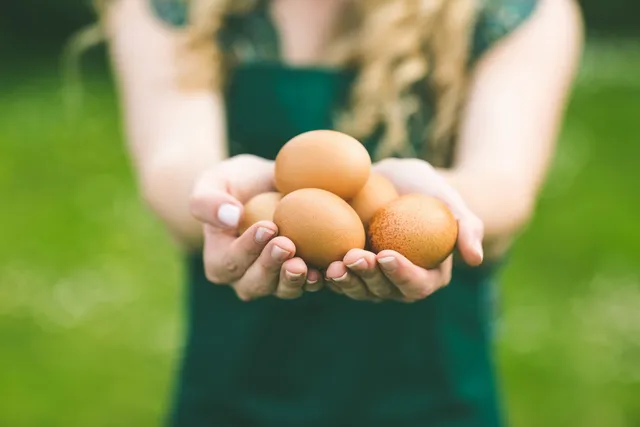 A woman holding three eggs in her hands.