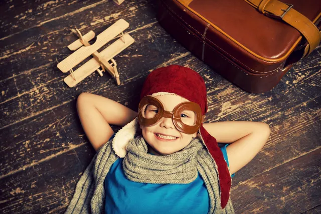 A child wearing goggles and a hat laying on the floor.