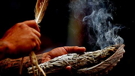 A person holding a feather and smoke in their hands.