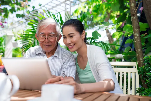 A woman and an old man looking at a laptop.