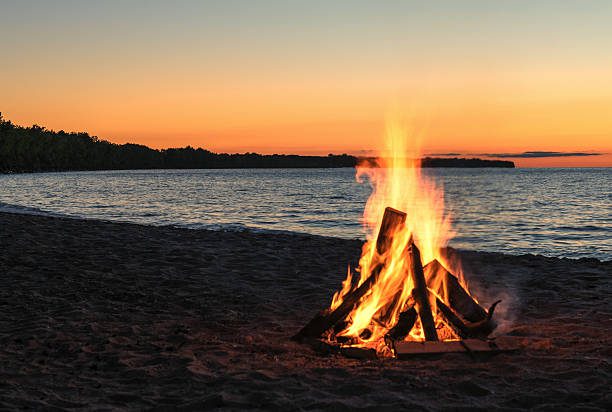 Bonfire on the sandy beach with beautiful sunset background